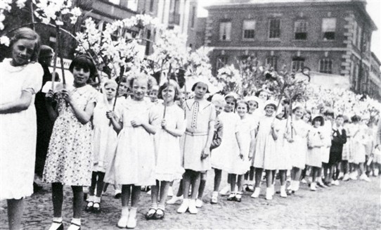Photo:9.  After the judging was over the devices paraded around the town preceded by children with garlands of flowers.  Pictured here among the procession in 1938 or 1939 is Jean Ragsdale (third from left).